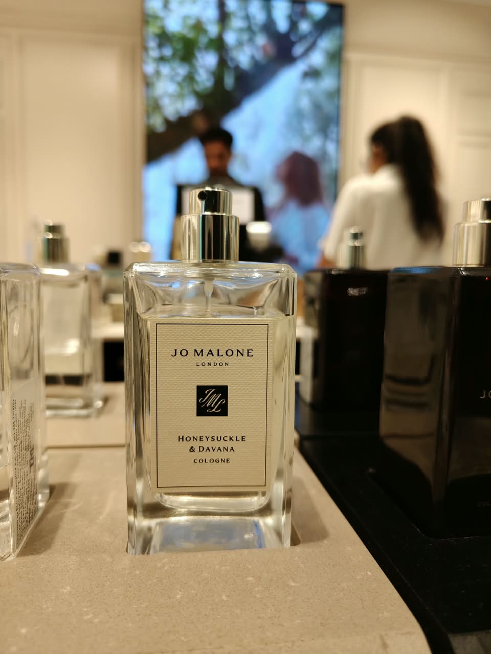 A perfume bottle in focus on a shop counter, the store blurred behind it